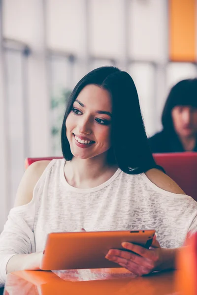 Hermosa chica trabajando en una tableta y sonriendo —  Fotos de Stock