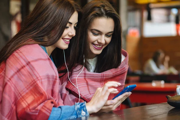 İki kız oturmuş akıllı telefonuyla müzik dinliyor. — Stok fotoğraf