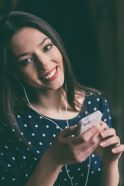 Vacker flicka lyssna på musik i telefonen med hörlurarna — Stockfoto