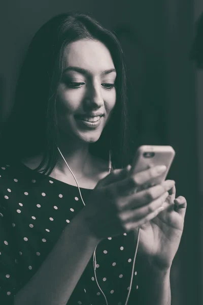 Vacker flicka lyssna på musik i telefonen med hörlurarna — Stockfoto