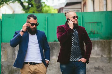 İki sakallı iş adamı telefona bakıyor.