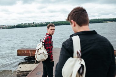 bir iskelede duran iki genç adam