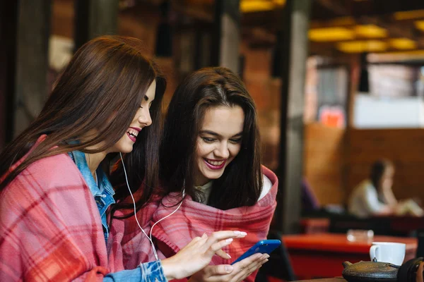 Zwei Mädchen sitzen und hören Musik mit einem Smartphone — Stockfoto