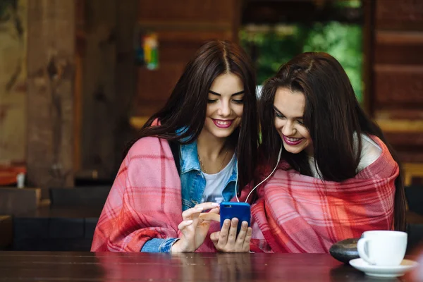 Två flicka sitter och lyssnar på musik med en smartphone — Stockfoto