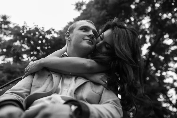 Joven pareja europea abrazándose en un banco del parque — Foto de Stock