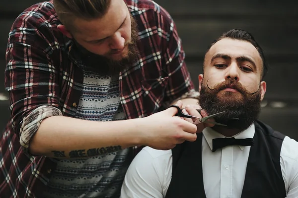 Barber shaves a bearded man — Stock Photo, Image