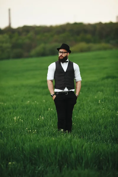Man med ett skägg och solglasögon går på fältet — Stockfoto