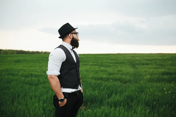 Man with a beard and sunglasses walking on the field — Stock Photo, Image