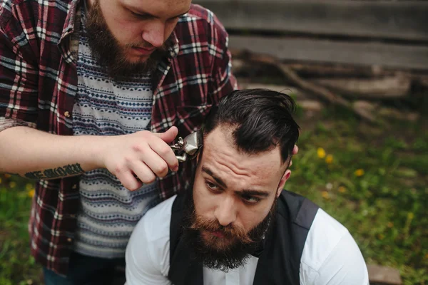 Barbero afeita a un hombre barbudo — Foto de Stock