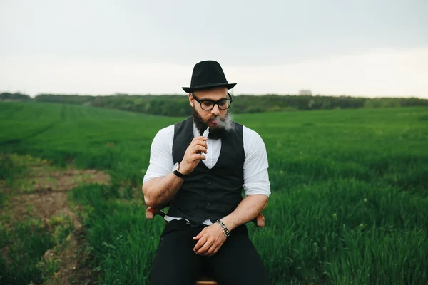 Людина з бородою курить електронну сигарету — стокове фото