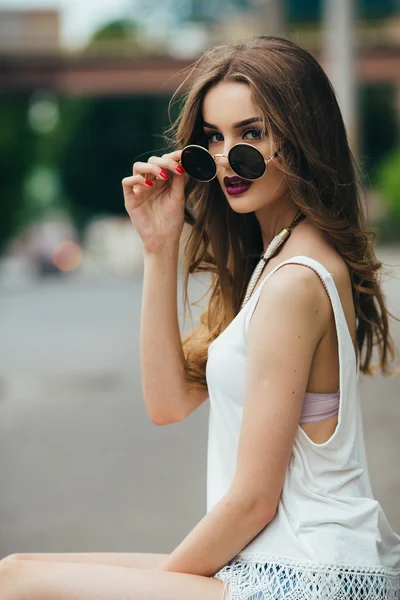 Mooi meisje in zonnebril zitten — Stockfoto