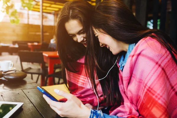 Две девушки сидят и слушают музыку со смартфона — стоковое фото