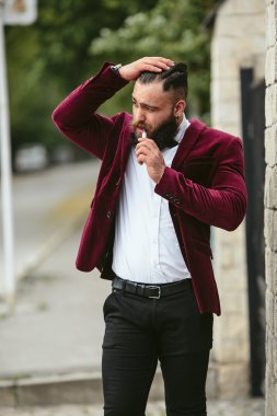 sakallı bir zengin adam elektronik sigara içiyor