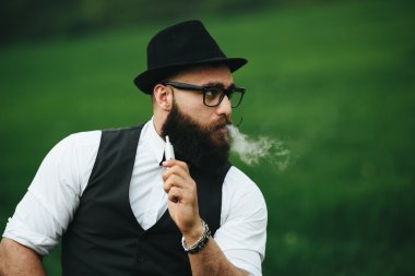 bir sakallı adam elektronik sigara içiyor