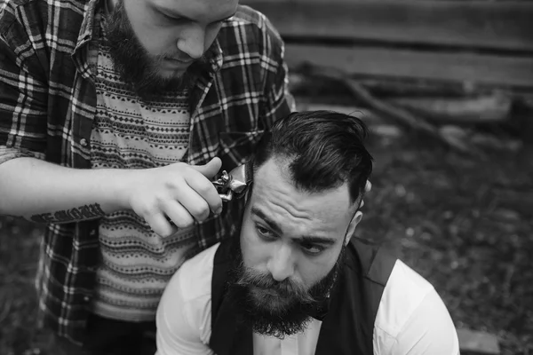 Barbero afeita a un hombre barbudo — Foto de Stock