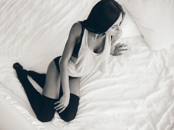 Belle jeune fille posant sur un lit blanc — Photo