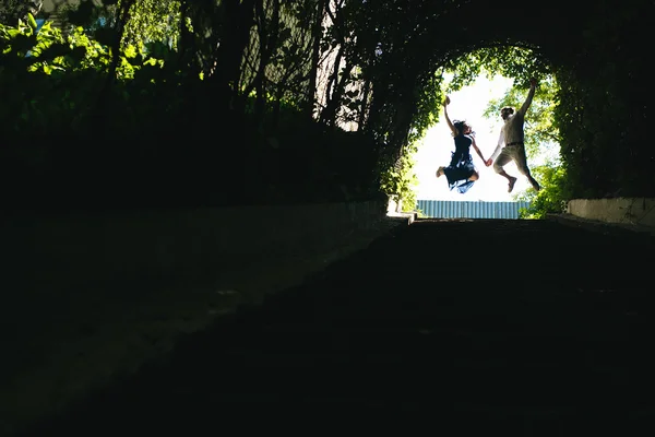 Coppia che salta in fondo al tunnel con alberi — Foto Stock