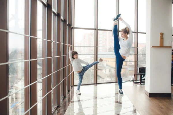 Mother learning daughter to make a high leg strech — Stock Photo, Image