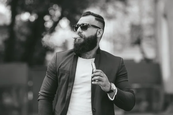 Man with a beard smokes electronic cigarette — Stock Photo, Image