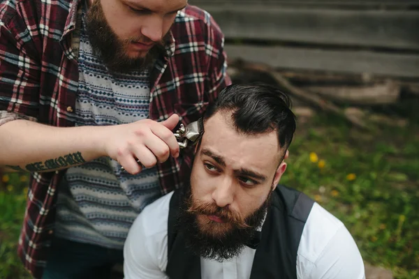 Barbero afeita a un hombre barbudo — Foto de Stock