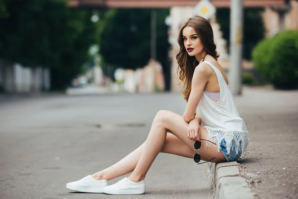 Menina bonita sentada em uma rua da cidade — Fotografia de Stock