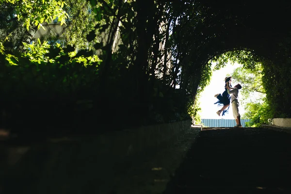 Casal pulando no final do túnel com árvores — Fotografia de Stock
