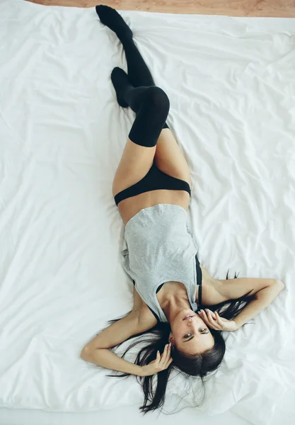 Mooi meisje die zich voordeed op een witte bed — Stockfoto