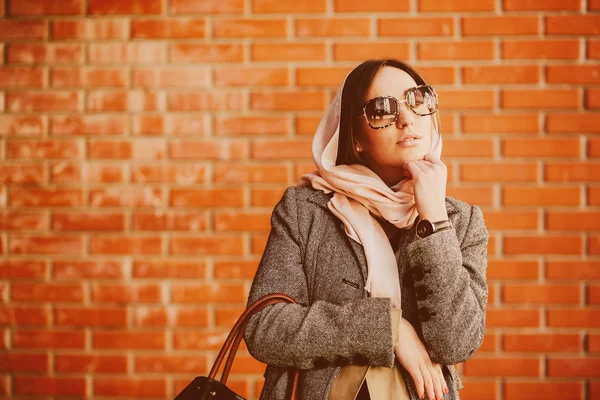 Girl posing on a background of red brick wall — Stock Photo, Image