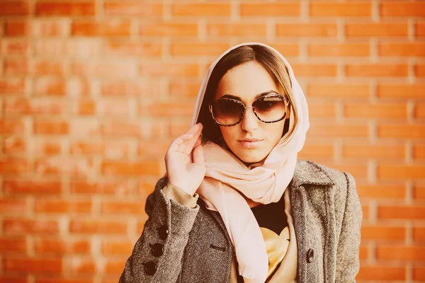 Girl posing on a background of red brick wall — Stock Photo, Image