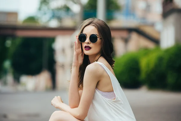 Красивая девушка в солнцезащитных очках сидит — стоковое фото