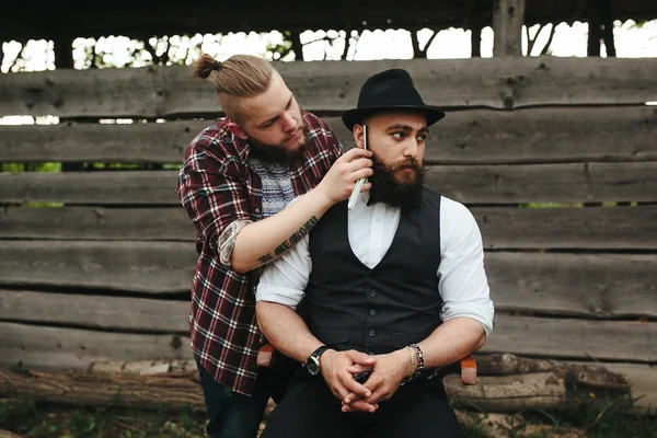 Barber shaves a bearded man — Stock Photo, Image