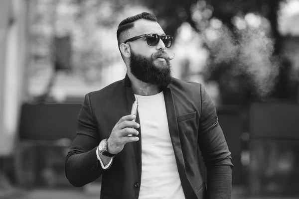 Man with a beard smokes electronic cigarette — Stock Photo, Image