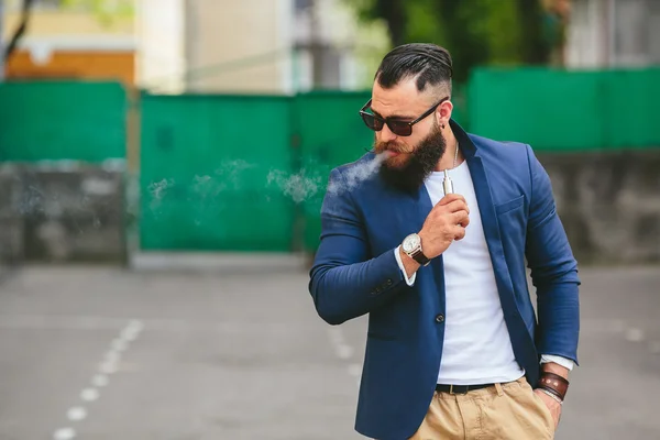 Man med ett skägg röker elektronisk cigarett — Stockfoto