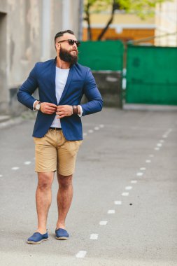Şık sakallı adam şehirde yürüyor.