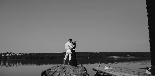 Abbracciare uomo e donna innamorati sul molo di legno — Foto Stock