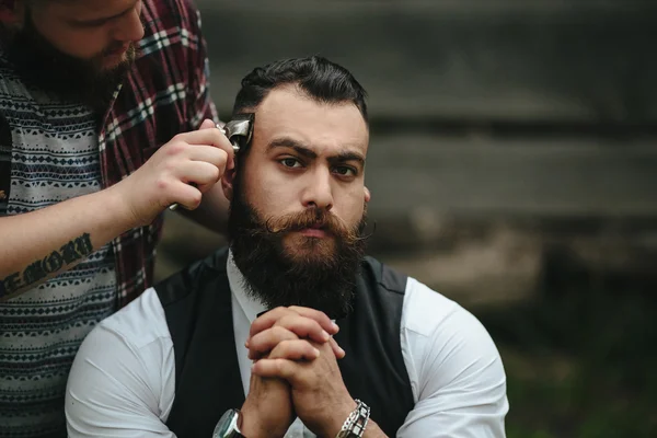 Barbero afeita a un hombre barbudo — Foto de Stock