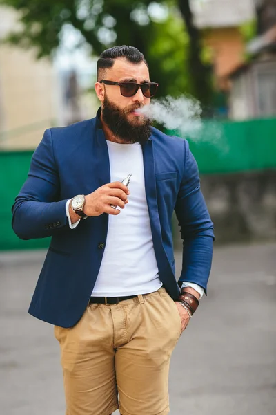 Man med ett skägg röker elektronisk cigarett — Stockfoto