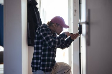 Kapıda diz çöküp sürgüyü takan adam tornavida kullanan eller, aktif tamir sahnesi, pratik odak, daire.