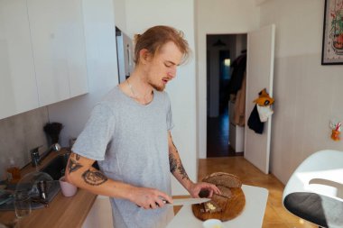 Mutfak tereyağı uygulaması, rahat bir sabah aktivitesi, sıcak mutfak atmosferinde ekmeğe tereyağı sürmek.