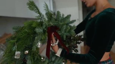 Şenlikli kadın dekorasyonu, kadın titizlikle kurdele ve süsleri sabah sıcağında şenlikli çelenk ile ayarlıyor.