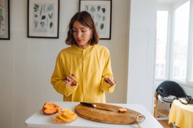 Portakal hazırlayan kadın anlamlı eller, eğitici duruş ve açık jestlerle yemek pişirmek için eğitici bir ortam yaratıyor.