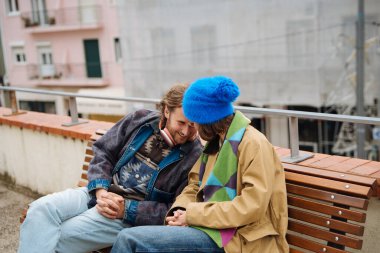 Ortaklar hassas bir anı paylaşır, bir çift birey, coşkulu sonbahar manzarası ve rahat kıyafetler arasında teselli edici jestler yapar.