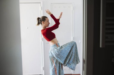 Şablonlu akıcı etek giyen bir kadın, dengeli dönüş ve sıvı kumaş gösteren bir profil görüntüsü, samimi bir daire köşesi, sakin.