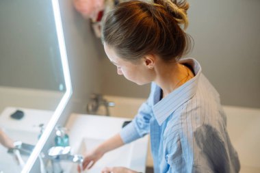Sakin estetisyen, banyo köşesine temizleyici sürüyor, LED ışığı ve sterilize edilmiş çevreyle yüz bakımı yapılıyor.