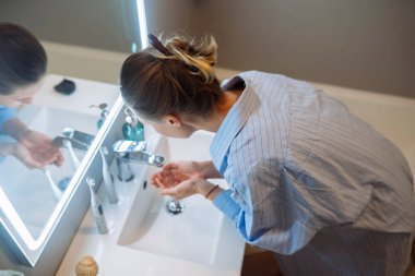 Temeli süngerle kaplayan Asyalı kadın, temelleri harmanlamaya ve aynanın önünde kızarmaya odaklanıyor.