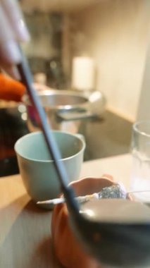 Seramik bardağa sıcak çikolata döken kadın, kabak kabağı ve bardaklarla mutfak tezgahından yükselen buhar.