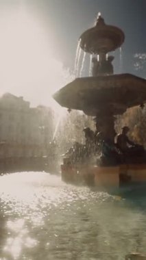 dinamik çeşme şehrin ufuk çizgisiyle sıçrıyor, güçlü jetler ve damlacıklar güneş tarafından aydınlatılıyor, parlayan havuz ve tarihi binalar.,