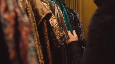 Tasarımcı, kadife perde, teatral dokular ve zengin metal iplikler arkasında pullu ve nakışlı giysiler seçiyor.
