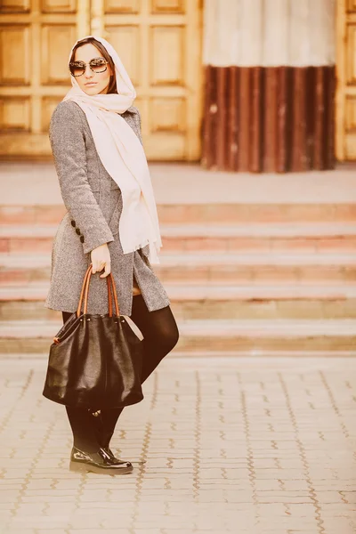 Ragazza in un cappotto posa su sfondo costruzione — Foto Stock