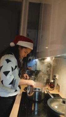 Fırında haşlanmış kadın Noel Baba şapkası takıyor, elinde kepçe, çorbada görünen havuçlar, sıcak tatil